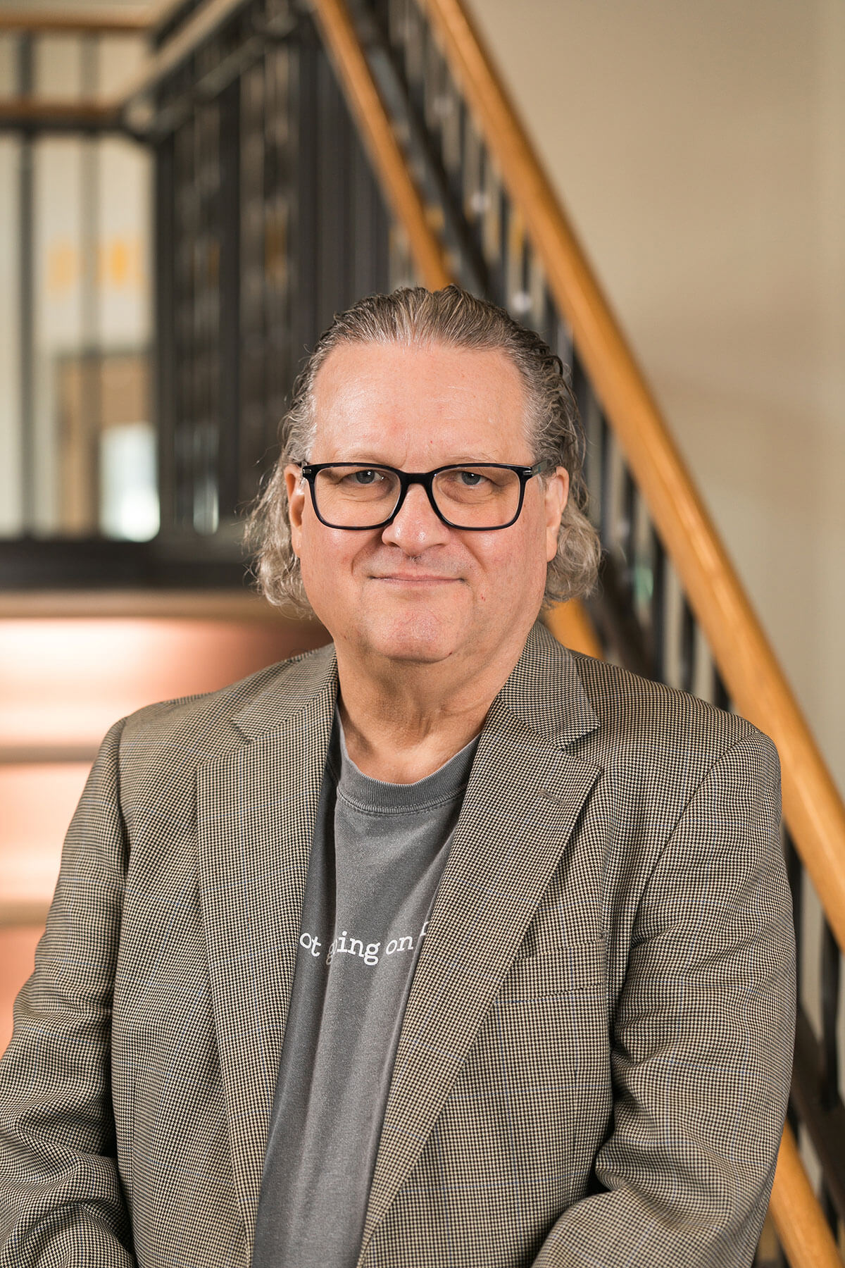 David Bader, man with grey hair, smiling in a professional headshot. Blue shirt, green jacket, teal background.