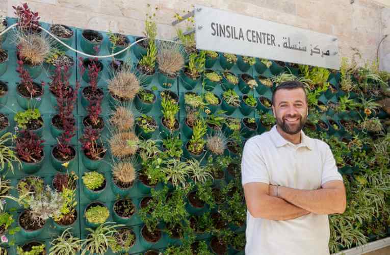 Happy man at Sinsila Center, proudly displaying the vibrant, sustainable green living wall installation.