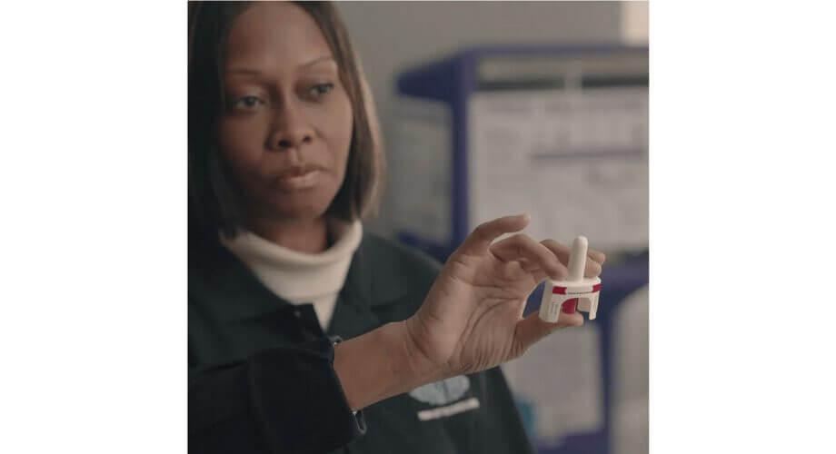Professional holds medical diagnostic device Professional woman holds a compact white medical diagnostic device with red markings in a laboratory setting.