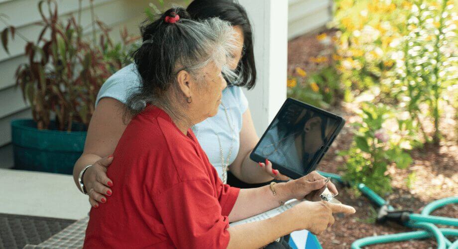 Digital Connection for Seniors: Tablet Use with Support Older woman on tablet for video call, supported by younger woman. Connecting digitally, fostering intergenerational support.