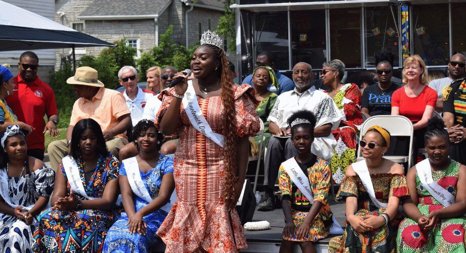 Miss Juneteenth speaks on stage at a vibrant Juneteenth celebration with pageant winners and attendees.