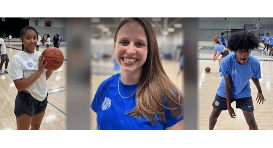 Smiling female coach with young diverse basketball players, girl with ball & boy in action, at an indoor youth camp.