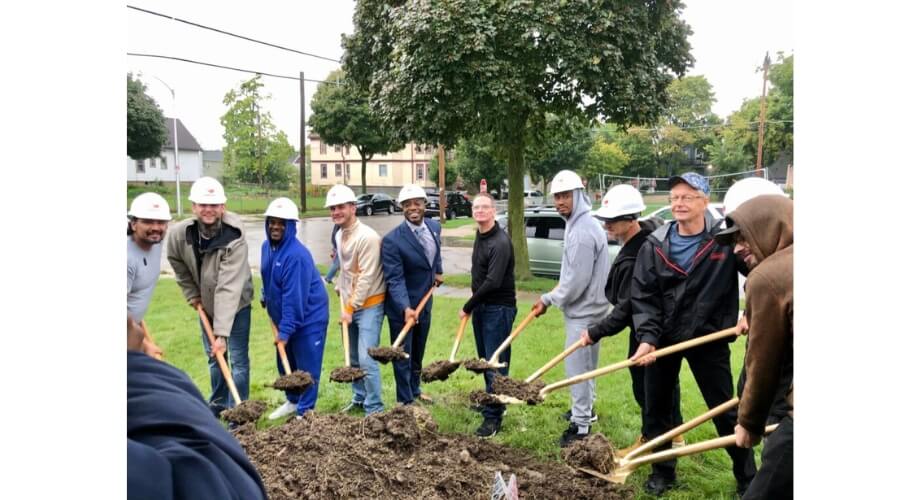 Serenity Inns Groundbreaking Ceremony Diverse team in hard hats break ground for new Serenity Inns project, smiling with shovels in dirt.