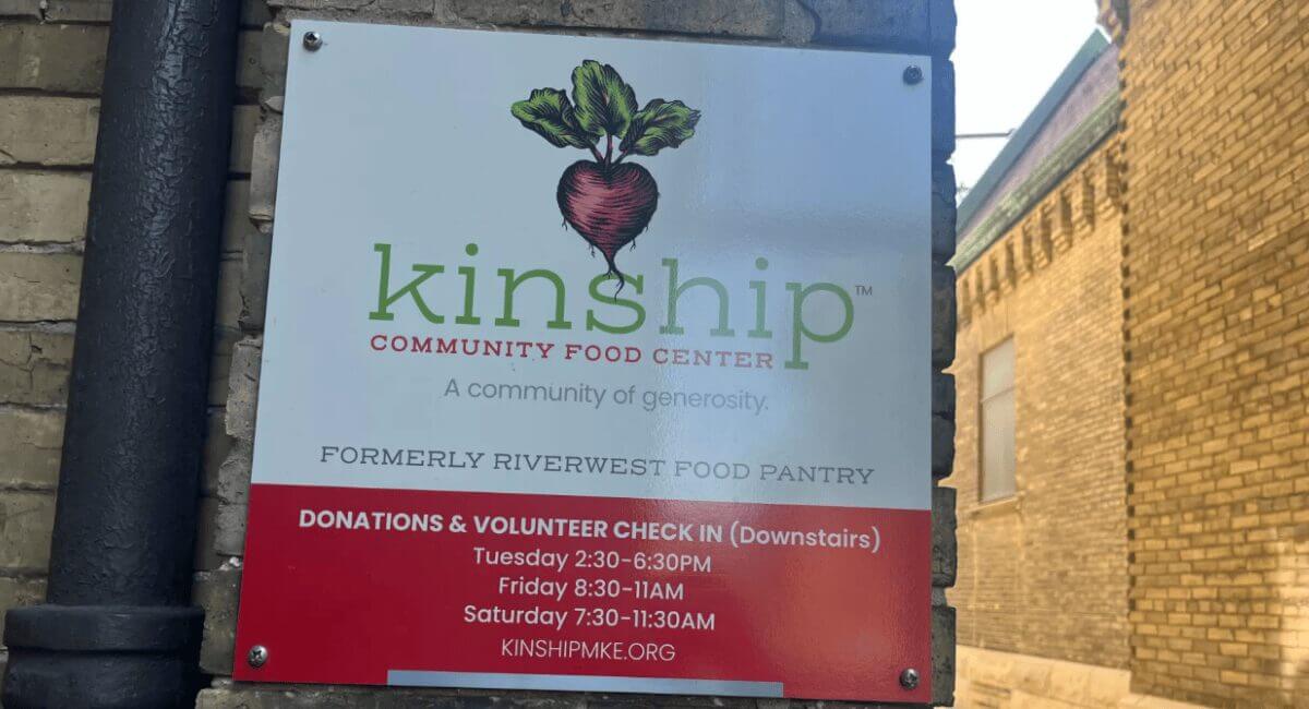 Kinship Community Food Center sign, formerly Riverwest Food Pantry, with beet logo and donation/volunteer hours.