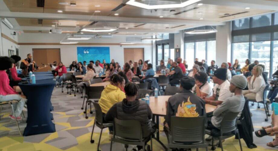 Diverse attendees engage with a speaker at a professional workshop in a modern conference room setting.