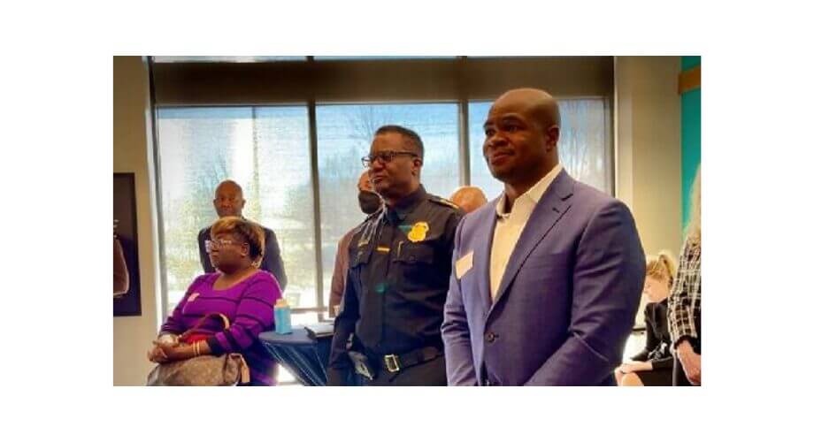 Police Officer & Professionals at Community Event Black police officer, man in blue suit, and woman in purple top attending an indoor community event with diverse attendees.