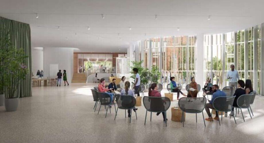 Diverse group conversing in a bright, modern collaborative lobby. Spacious interior with large windows and plants.