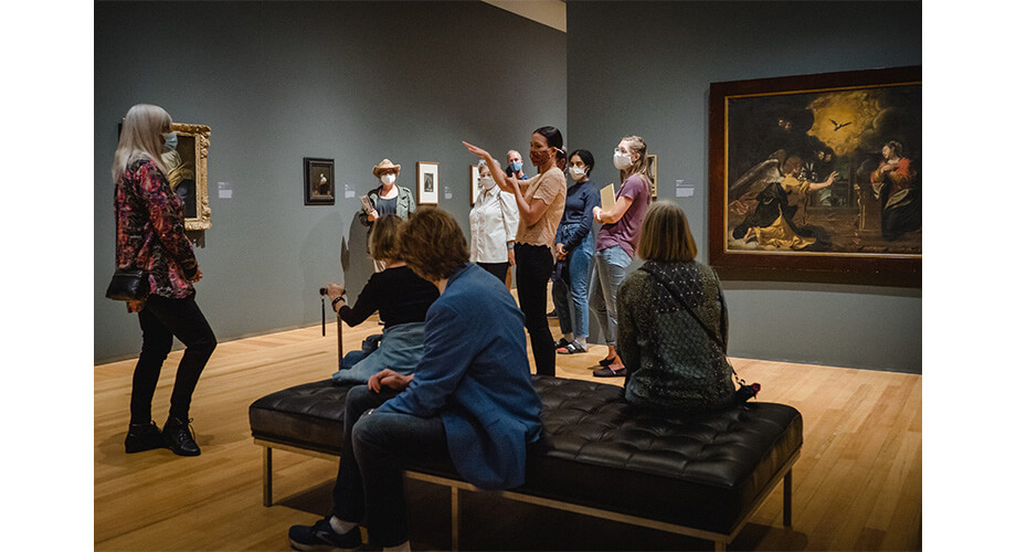 Agnes Reimagined Museum Tour: Guided Group Masked visitors explore the Agnes Reimagined exhibit with a guide, viewing various artworks and paintings.