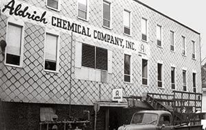 Vintage Aldrich Chemical Company building, early headquarters, with old truck. Black and white photo.