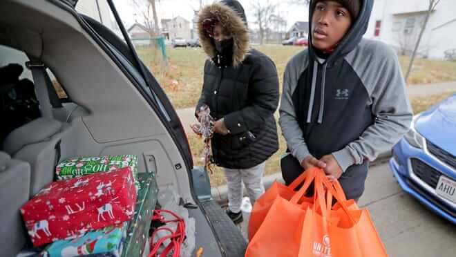 Habitat for Humanity Xmas Gifts & Volunteers Habitat for Humanity volunteers loading wrapped Christmas gifts into a car for a holiday drive.