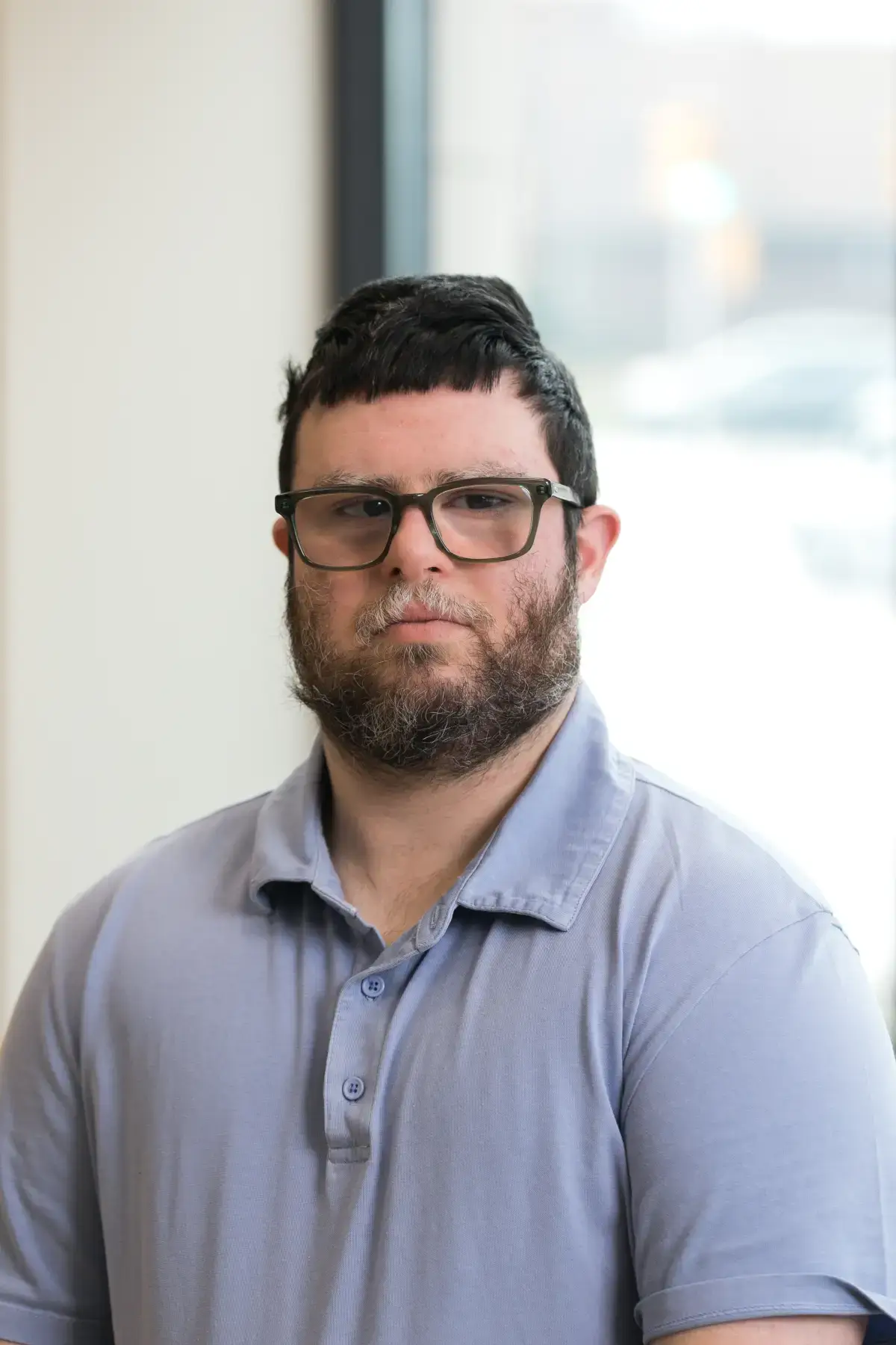 Alex Bader professional headshot. Man with glasses, beard, and light blue polo shirt.