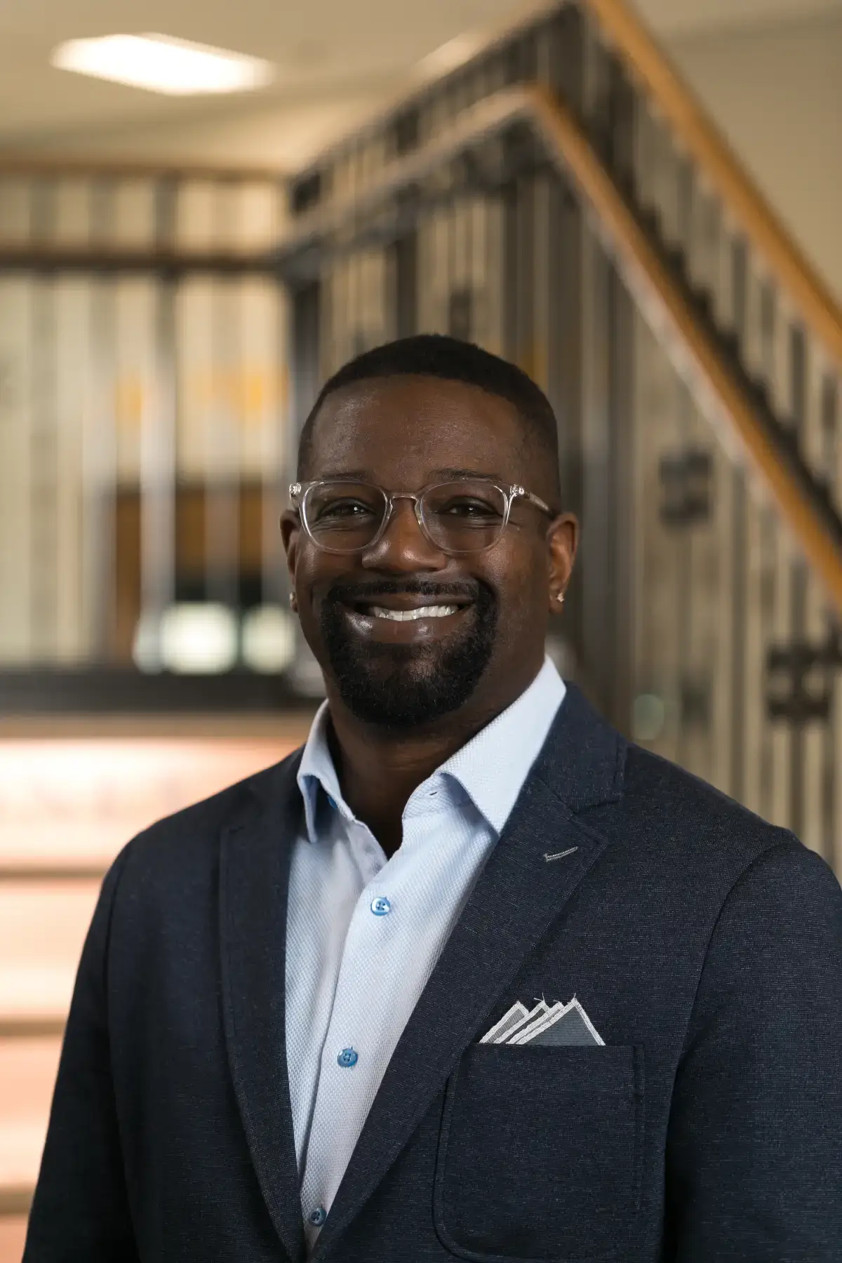 Brandon A. Wigley, JD, smiling professional headshot. Black man in glasses, blue suit, office background.