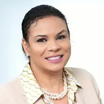 Jeannie Fenceroy, smiling business professional in a beige blazer, patterned blouse, and pearl necklace.
