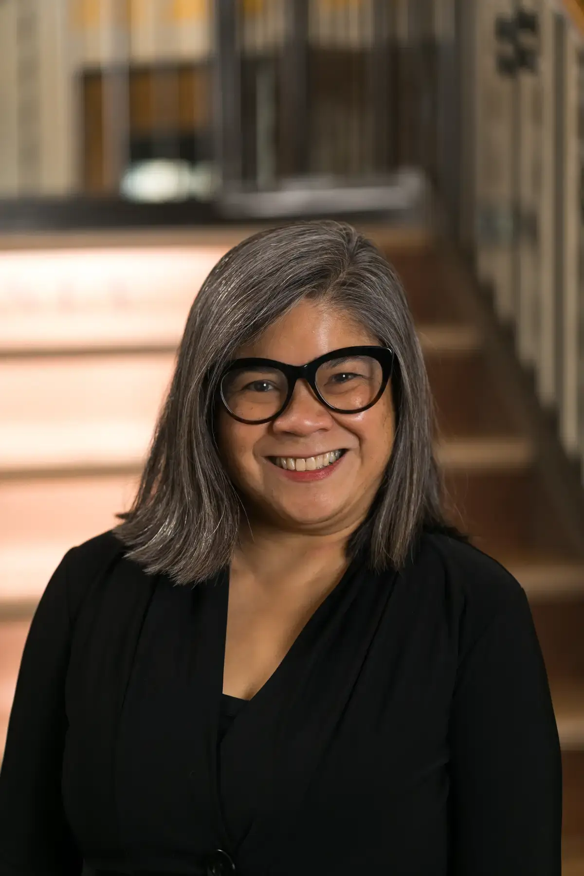 Merilou V. Gonzales, an Asian woman with gray hair and glasses, smiling confidently in a professional headshot.