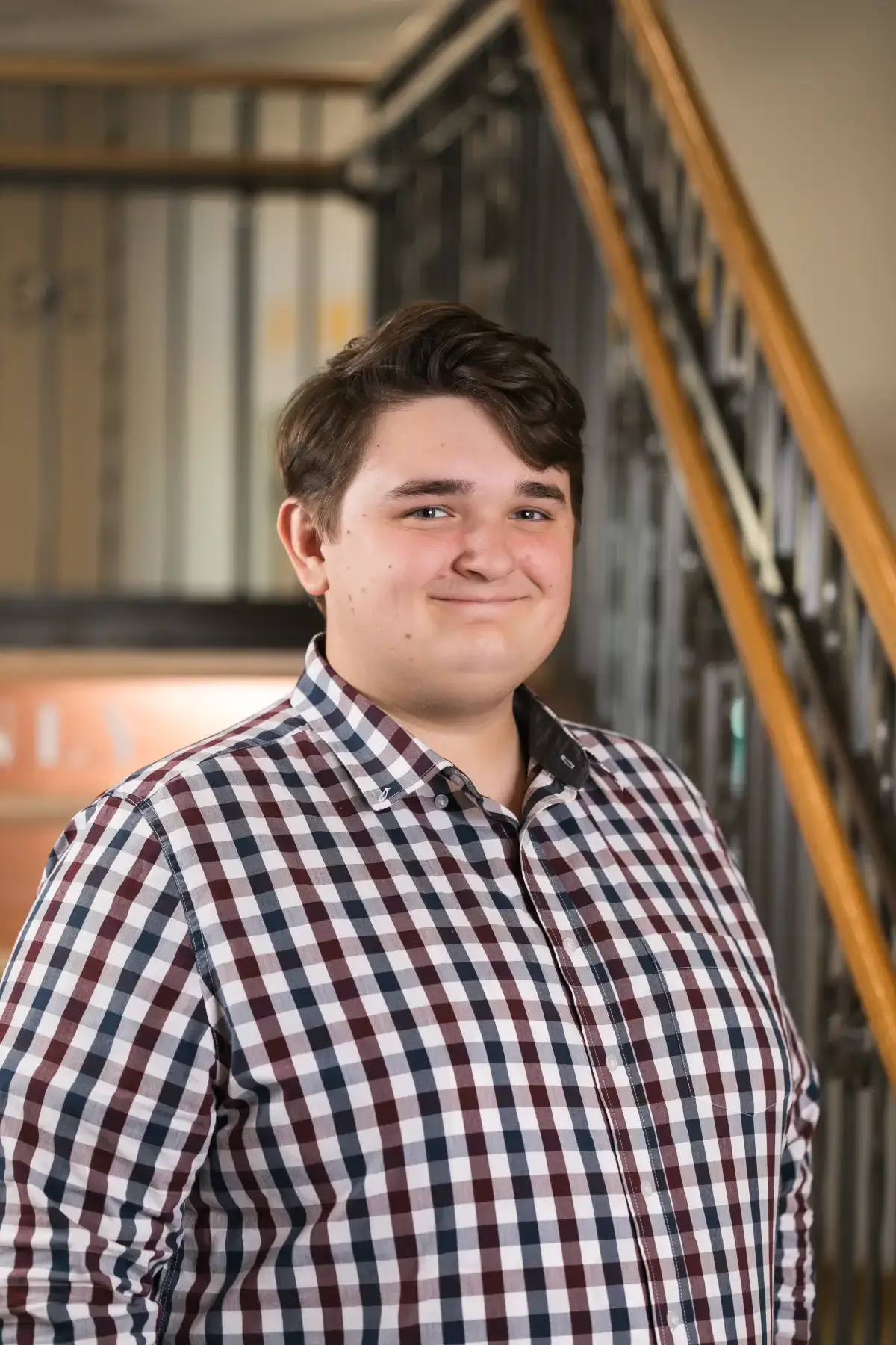 Sean Ogrosky's professional headshot, smiling in a maroon and blue plaid shirt. Ideal for corporate profiles.