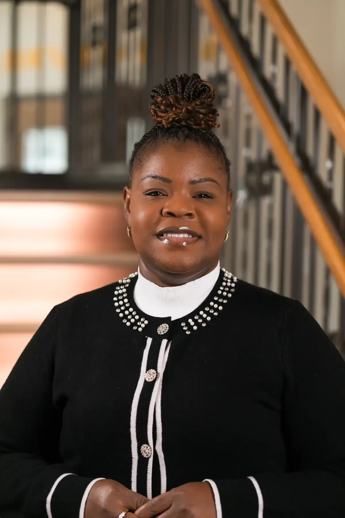 Professional headshot of Tamara Lynette Hogans, smiling confidently in a black pearl-embellished cardigan.