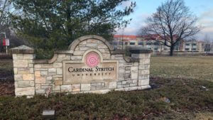 Cardinal Stritch University stone entrance sign with logo, campus architecture and winter trees in background.