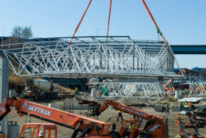 HBF project construction in Spring 2012, with cranes hoisting a massive steel truss into place over the site.