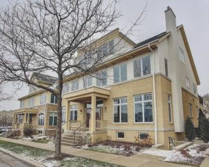 Modern yellow brick townhome exterior with light siding, large windows, bare tree, and patchy snow in winter 2012.