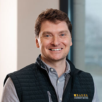Audra Brennan smiling professional blonde woman wearing a multi-strand pearl necklace.
