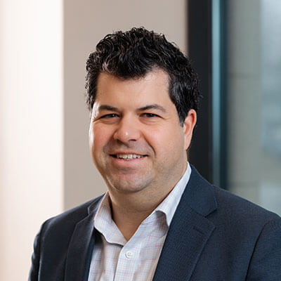 Jeannie Fenceroy, smiling business professional in a beige blazer, patterned blouse, and pearl necklace.