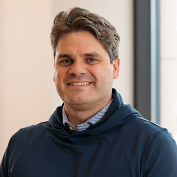 Graham Andersong in a red Milwaukee jacket and checkered shirt, looking professional against a white background.