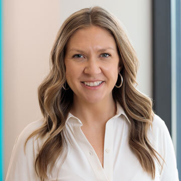 Suzanne Spencer, a professional woman, smiles confidently in a pink business suit for her corporate portrait.