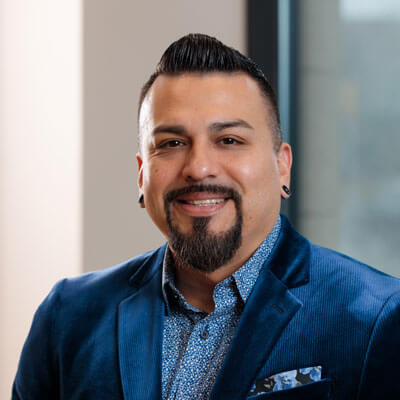 Suzanne Spencer, a professional woman, smiles confidently in a pink business suit for her corporate portrait.